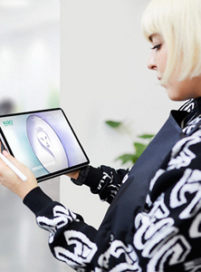 A female hair stylist holding a tablet displaying the Green Mirror escape room game